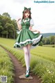 A woman in a green and white dress standing in a field.