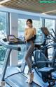 A woman is standing on a treadmill in a gym.