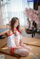 A woman in a white and red outfit sitting on a tatami mat.