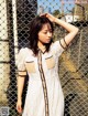 A woman standing in front of a chain link fence.