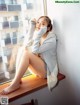 A woman sitting on a window sill with her legs crossed.