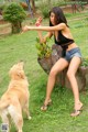 A woman sitting on top of a tree stump next to a dog.