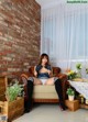 A woman sitting on a chair in front of a brick wall.