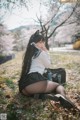A woman sitting on the ground in a park.