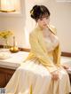 A woman in a yellow robe sitting on a kitchen counter.