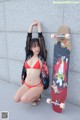 A woman in a red bikini posing next to a skateboard.