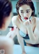 A woman applying lipstick in front of a mirror.