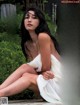 A woman in a white dress sitting on a wooden deck.