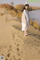 A woman standing on top of a sand dune next to a river.