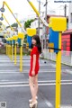 A woman in a red dress standing in the middle of a street.