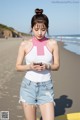 a woman standing on a beach looking at her phone