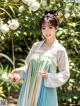 A woman in a blue and white dress standing in front of flowers.