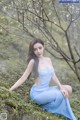 A woman in a blue dress sitting on the ground.