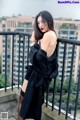 A woman in a black dress standing on a balcony.