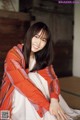 A woman sitting on the floor wearing a red and white striped jacket.