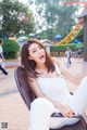 A woman sitting on a chair in a park.